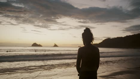 Hombre-Solitario-Frente-A-Una-Playa-Tropical-Reflexionando-Durante-La-Puesta-De-Sol