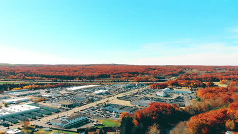 4K Drone Footage the colors of fall, big red and orange leaves as far as the eye can see from a birds eye-view, we see the distant businesses as we pan across the horizon