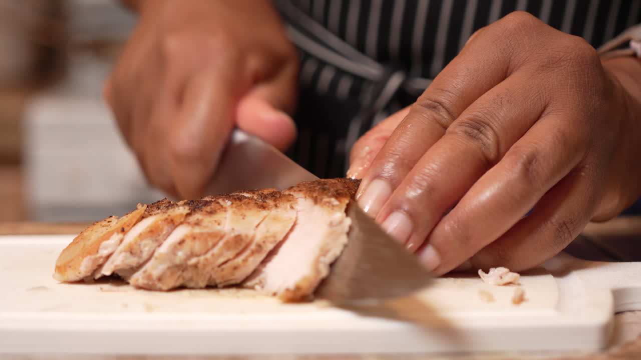 Affettare pollo con un coltello da macellaio su un tagliere - isolato