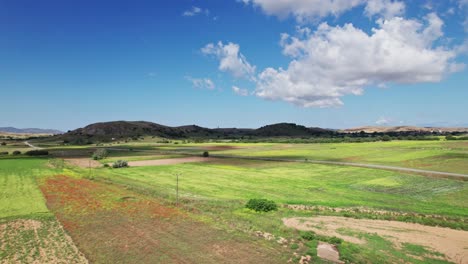 Wolkenschatten-Verdunkeln-Die-Graslandschaft,-Während-Ein-Einsames-Auto-Eine-Leere-Straße-Entlangfährt