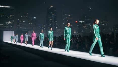 a stunning fashion showcase under city lights: models in vibrant outfits strut the runway, highlighting contemporary style against a glamorous urban backdrop
