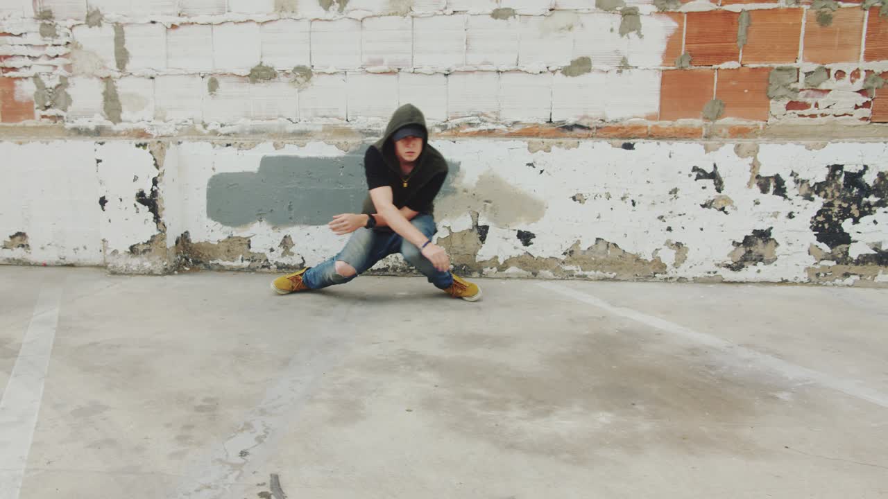 Man hip hop dancing outside in city in front of brick wall