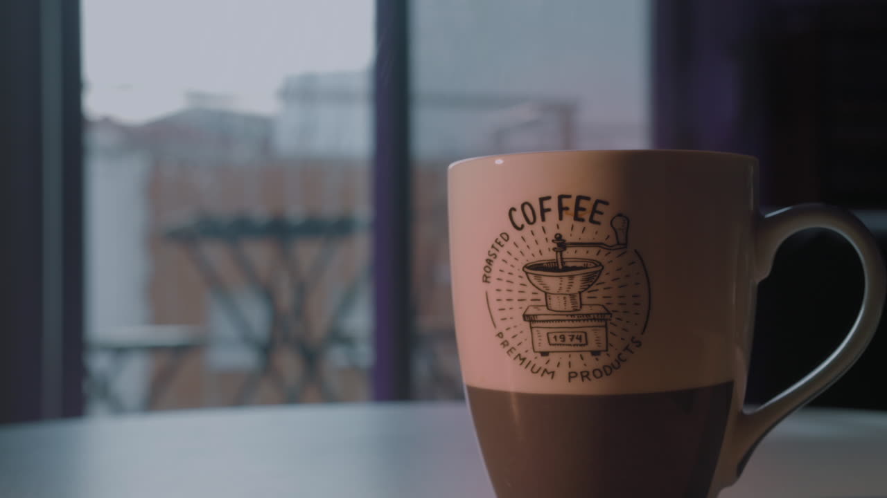 Tazza di caffè fumante su un tavolo accanto a una finestra