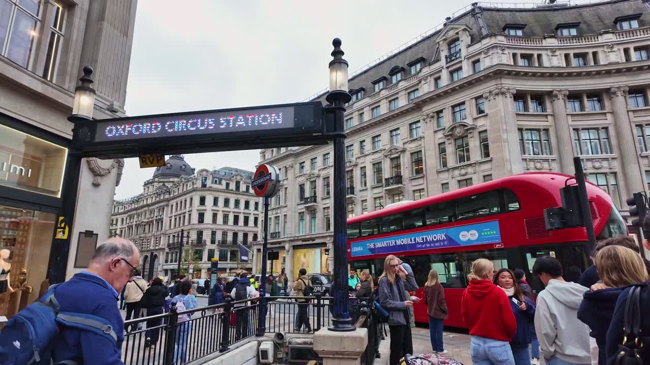 Panning movement around the Oxford Circus Station sign with urban street crowd, London, England.