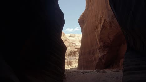 tilt down handheld wide shot revealing a large opening from a hike through a tall orange sandstone slot canyon in buckskin gulch in southern utah near arizona on a warm sunny spring morning