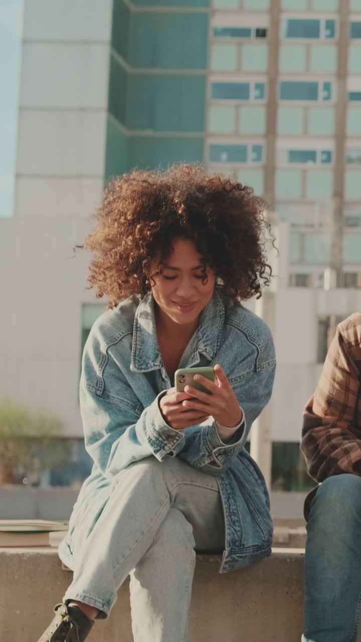 Donna con i capelli ricci che usa il telefono all'aperto