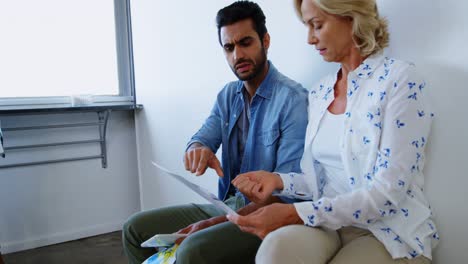 Male-and-female-executives-discussing-over-document