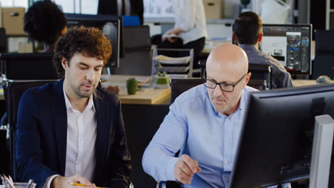 empleados de oficina caucásicos hablando y trabajando en la computadora en la oficina