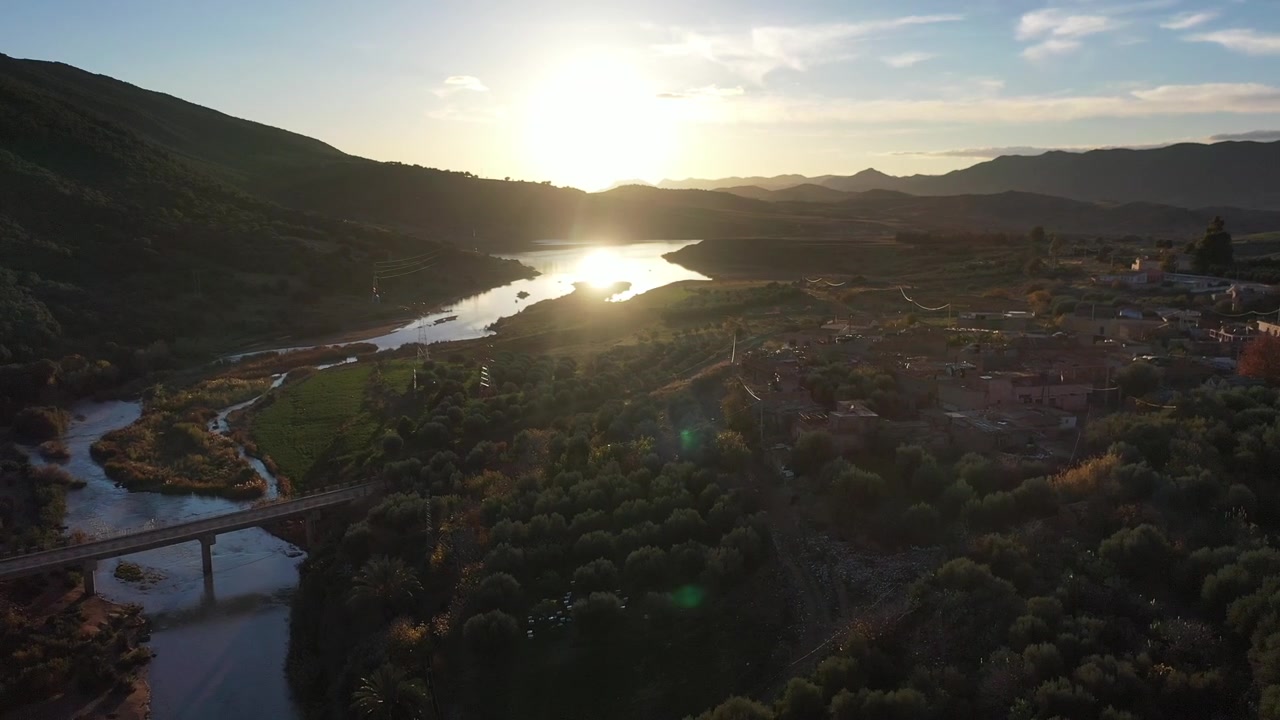 Vista aerea cinematografica con drone del riflesso del tramonto su una valle fluviale e un paesaggio montano nel Medio Atlante, Marocco, ideale per progetti di viaggio, natura e avventura