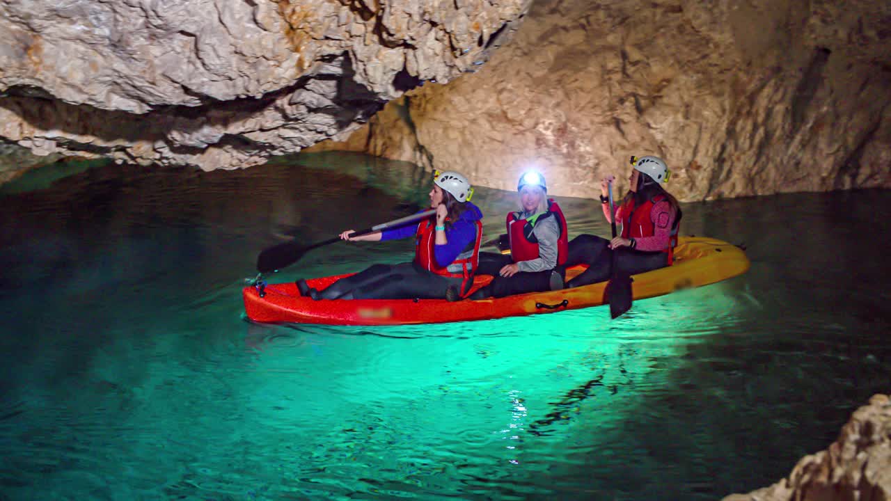 Tre giovani donne avventurose in kayak in una grotta sotterranea. Carrellata