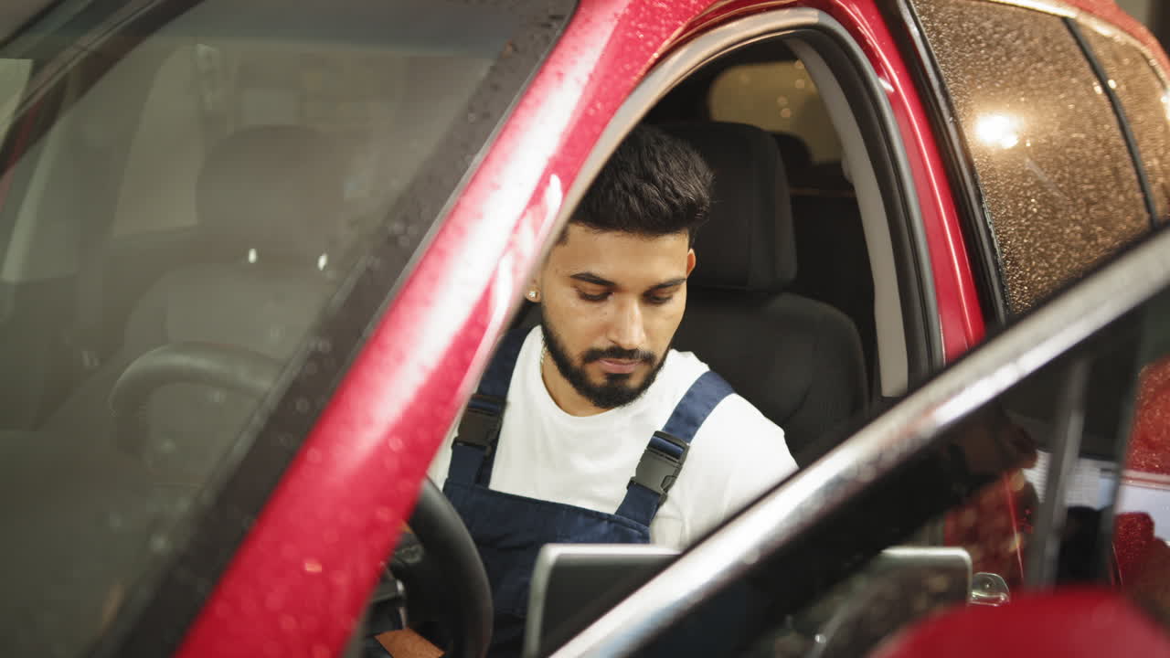 hombre inspeccionando un coche en un taller de reparación