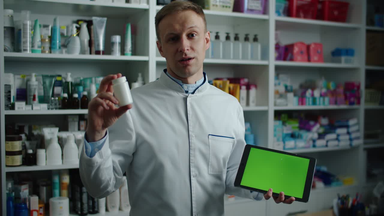 남성 약사는 약국에서 녹색 화면을 가진 디지털 태블릿을 들고 약을 사용하도록 권장합니다. 남성 초상화