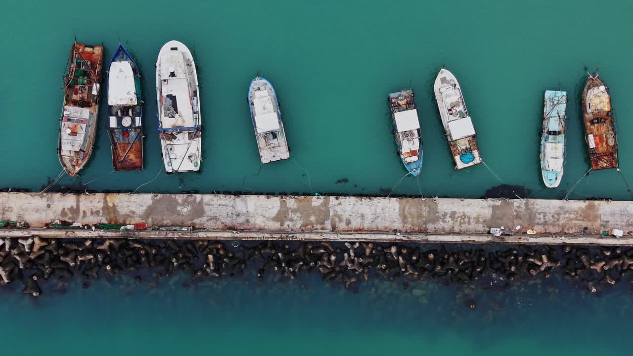 Boats docked along a pier near the shore during daylight hours