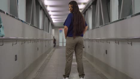 Una-Joven-Latina,-Luciendo-Un-Estilo-De-Moda-Urbana,-Recorre-Una-Pintoresca-Pasarela-Peatonal-En-Puerto-España,-Trinidad.