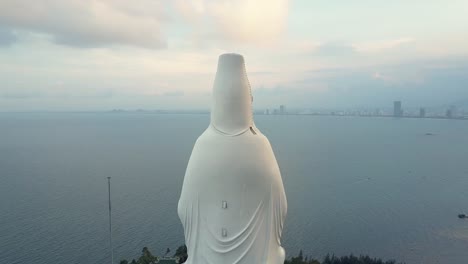 aerial round close huge white buddha statue facing ocean