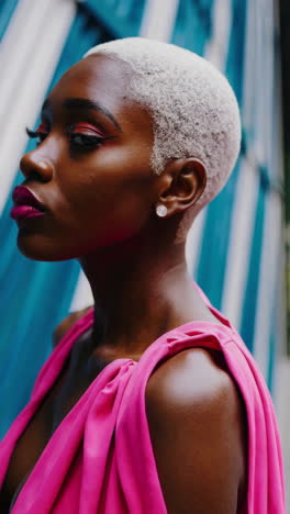 stylish woman in pink with blonde buzz cut and bold makeup