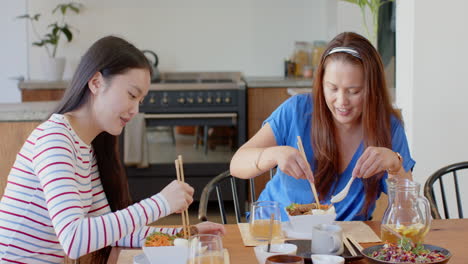 Eating lunch together, asian mother and daughter enjoying meal at home dining table