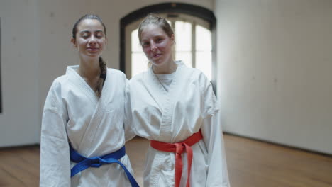 front view of happy girls in kimonos standing in gym and hugging