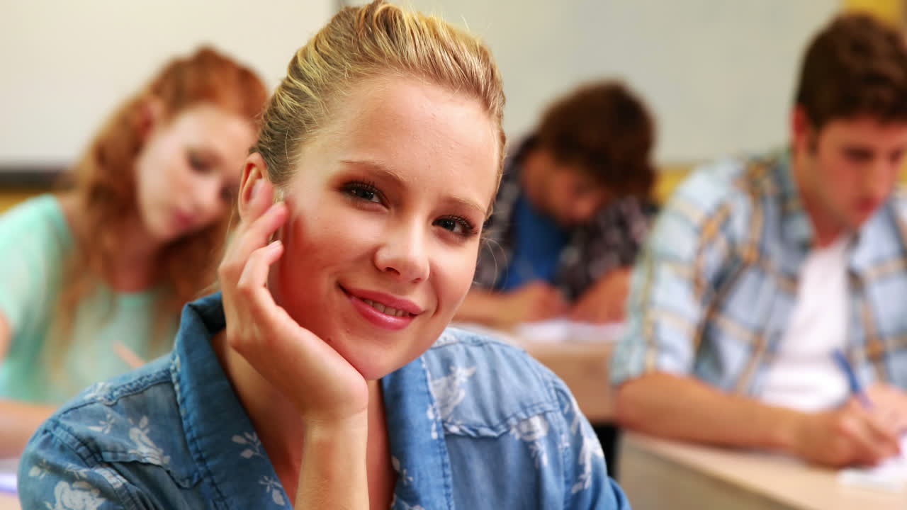 Thoughtful student smiling to camera in classroom