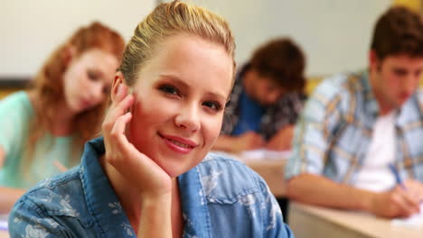 Thoughtful-student-smiling-to-camera-in-classroom