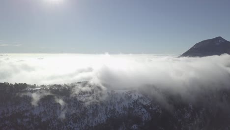 aerial view of clouds rolling over a snowy mountain range