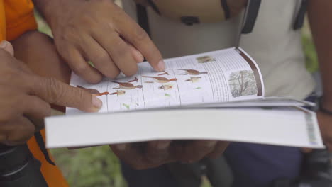 two guys pointing at book of birds and wildlife