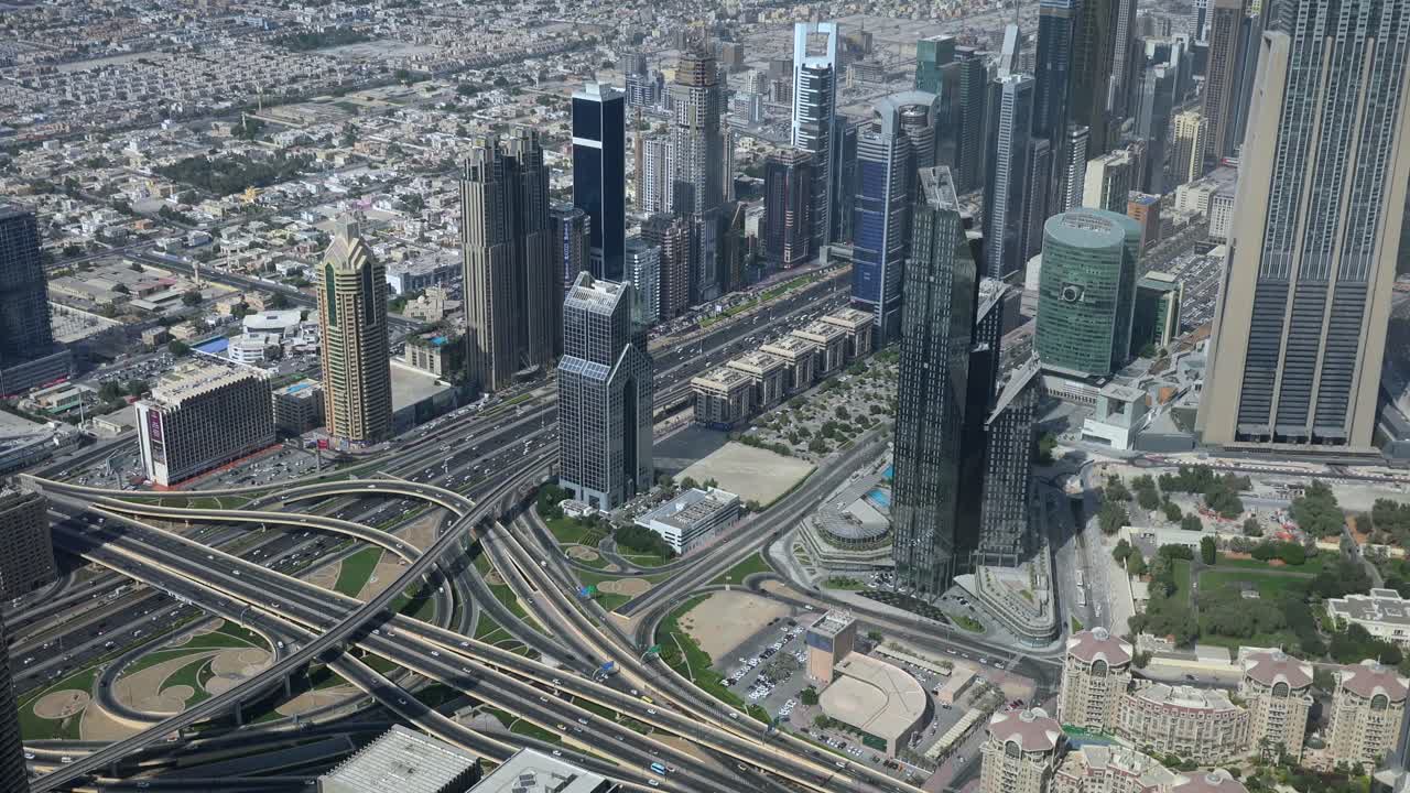 Aerial view of a bustling cityscape with modern skyscrapers, intricate highway interchanges, and urban greenery, showcasing a vibrant metropolitan area