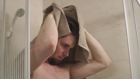 man drying his hair in the shower