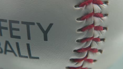 cinematic beautiful smooth macro shot of a white base ball, close-up on red stitches, safety ball, baseball on a shiny stand, professional studio lighting, 4k video pan right