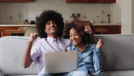 una pareja de adolescentes africanos mirando su portátil, leyendo las noticias, sintiéndose felices.