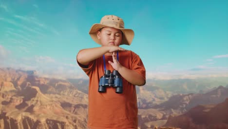 asian boy with a hat and binoculars shaking head showing time out gesture while traveling at the top of mountain. boy researcher, travel tourism adventure concept