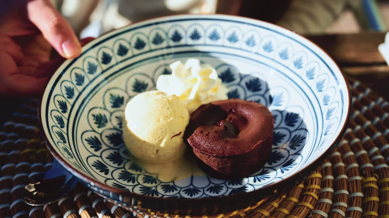Woman spinning a plate with warm chocolate fondant served with vanilla ice cream and whipped cream