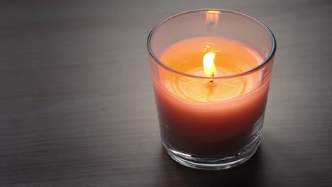 la llama de una vela ardiente parpadea de una ligera brisa al anochecer. el concepto de comodidad, decoración interior y celebración en el hogar