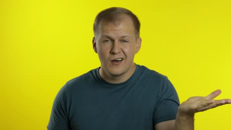 Portrait of young caucasian man posing in t-shirt. Dissatisfied guy puts hand on face, facepalm