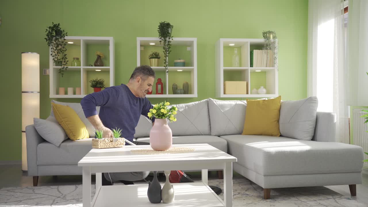 성숙한 남자가 현대적인 거실에서 카 ⁇ 을  ⁇ 고, 진공청소기로 청소하고 있습니다.