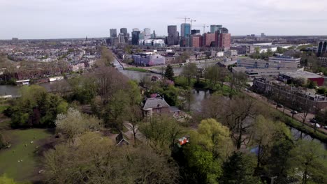 Backwards-aerial-movement-showing-financial-district-cityscape-of-Utrecht-revealing-Oog-in-Al-park-in-the-foreground-during-a-sunny-day