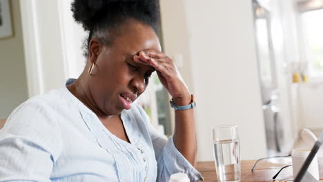 African-american-senior-woman-having-video-call-and-holding-medicines-in-sunny-room,-slow-motion