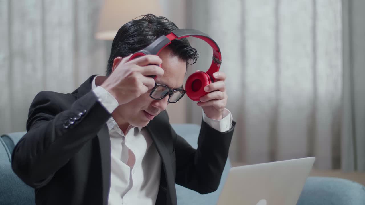 집에서 노트북으로 일하면서 헤드폰으로 음악을 듣고 춤을 추는 재과 쇼트를 입은 아시아 사업가