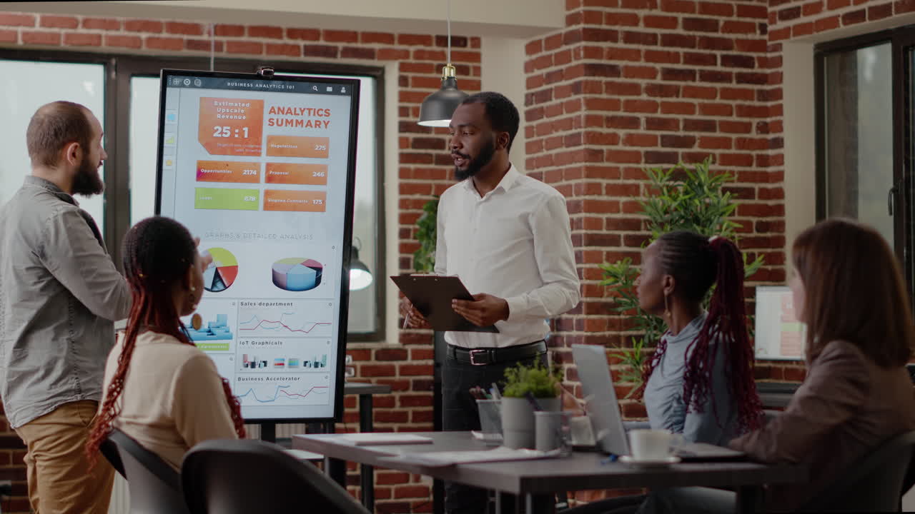 Colleagues discussing business presentation with analysis on monitor