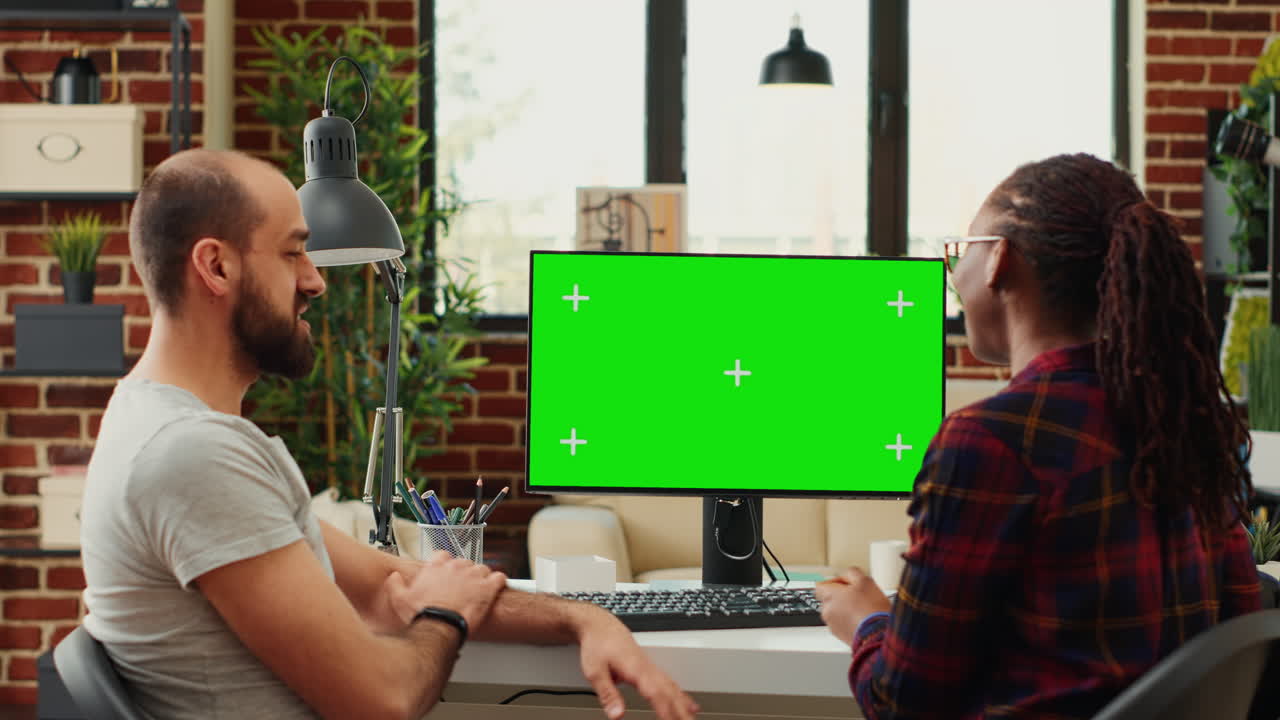 Diverse colleagues working with greenscreen display on computer
