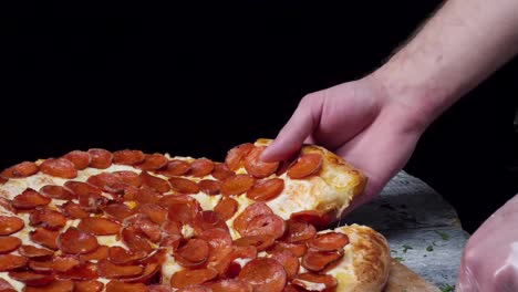 la mano sosteniendo una rebanada de pizza de pepperoni