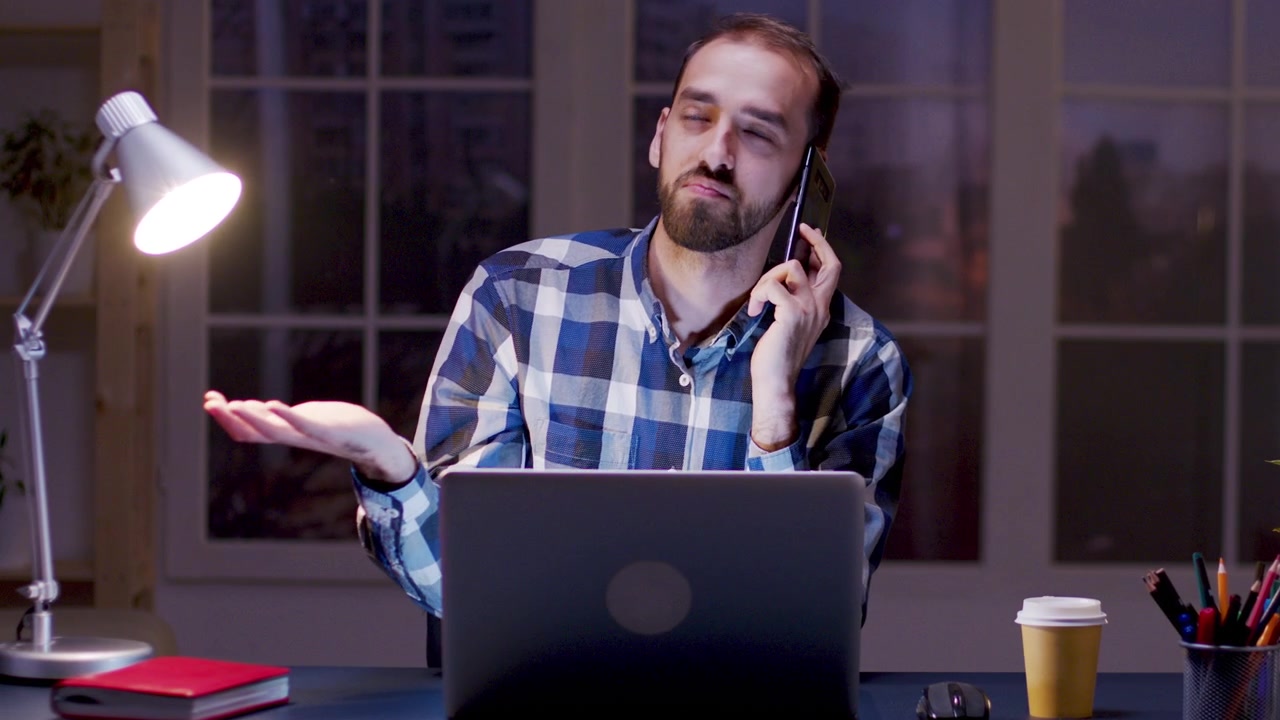 Uomo che parla al telefono mentre lavora fino a tardi in ufficio