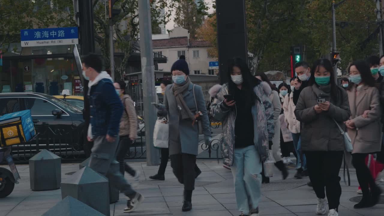 Masked pedestrians cross a busy crosswalk in downtown Shanghai amid new variant omicron COVID-19 coronavirus outbreak in Shanghai, China.