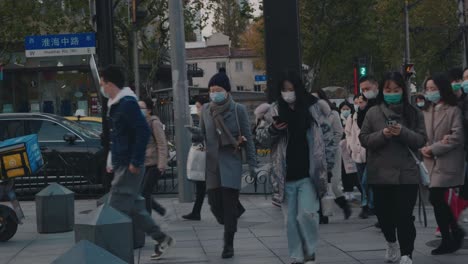 masked pedestrians cross a busy crosswalk in downtown shanghai amid new variant omicron covid-19 coronavirus outbreak in shanghai, china.