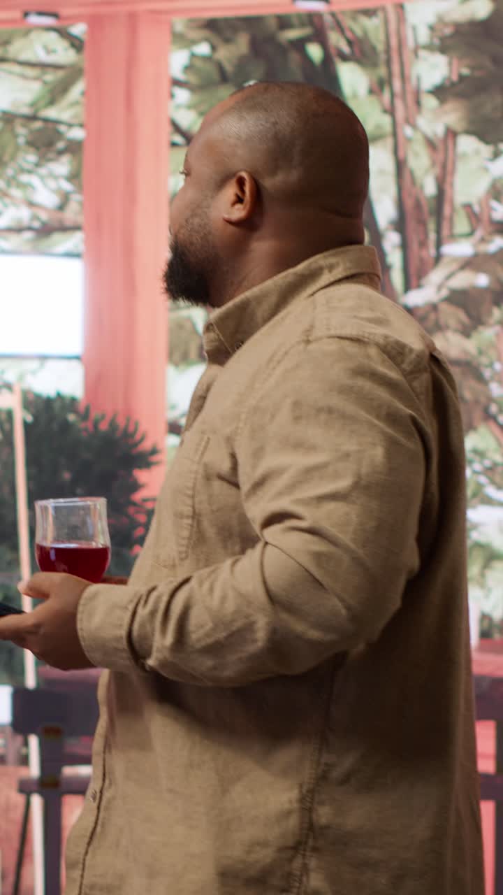 African American Man Holding Red Wine and Using Smartphone