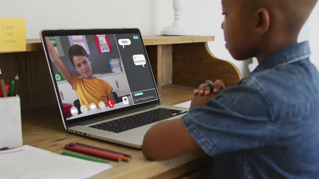 Schoolboy using laptop for online lesson at home, with his colleague and web chat on screen