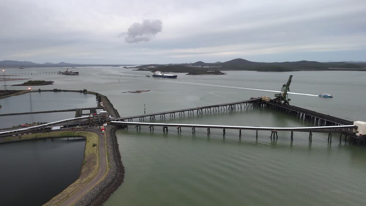 Flyover pier at Gladstone coal terminal toward ship leaving port, QLD