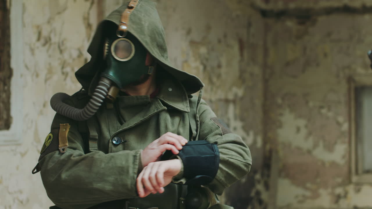 A Man In An Abandoned Building Looking At The Readings On His Arm He Was Wearing A Gas Mask And Prot