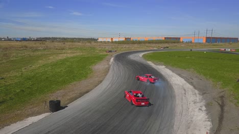 two red racing drift cars doing a parallel drift on a track