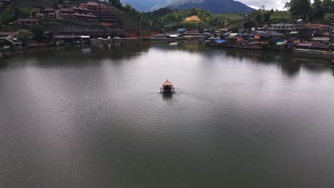 Aerial-rotating-shot-of-people-boating-on-the-lake-at-daytime-in-a-boat-with-oars-in-Ban-Rak-Tai,-Mueang-Mae-Hong-Son,-Thailand